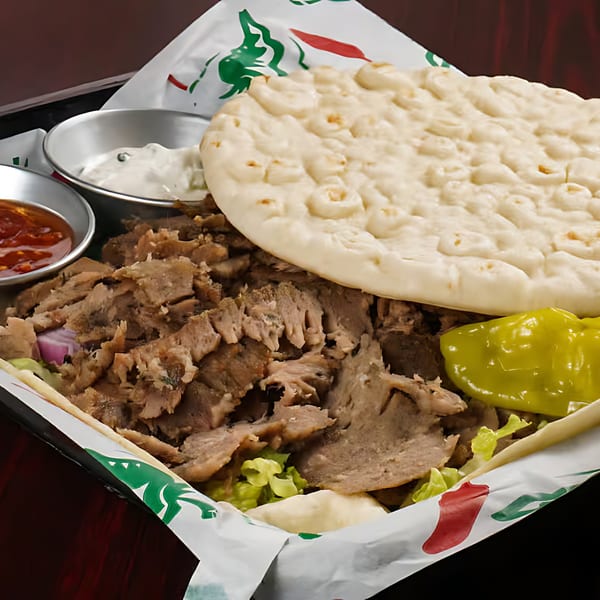 A gyro platter from Sandwich Planet with sliced meat, pita bread, lettuce, and two dipping sauces.