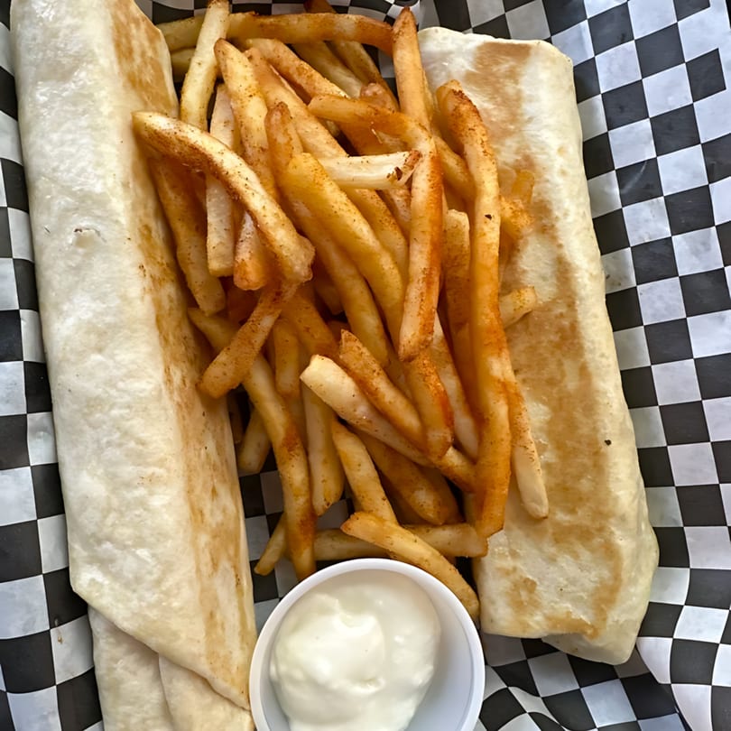 Two Sandwich Planet wraps with seasoned fries and a side of white dipping sauce in a checkered basket.